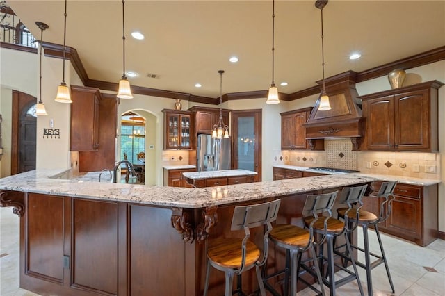 kitchen with a peninsula, stainless steel appliances, custom exhaust hood, arched walkways, and ornamental molding