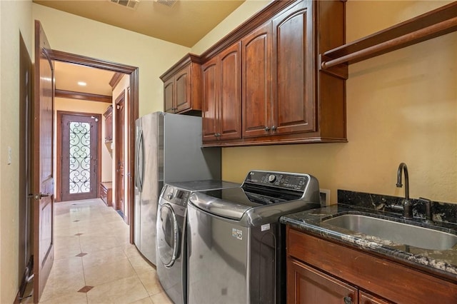 clothes washing area with light tile patterned floors, a sink, cabinet space, visible vents, and independent washer and dryer