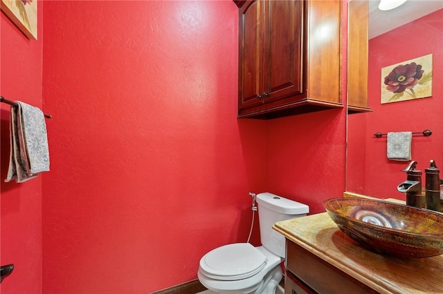 bathroom with vanity, toilet, and a textured wall