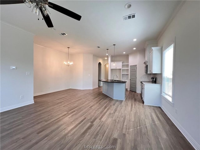 unfurnished living room with hardwood / wood-style floors, ceiling fan with notable chandelier, sink, and crown molding