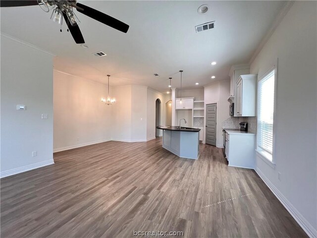 unfurnished living room with hardwood / wood-style floors, ceiling fan with notable chandelier, sink, and crown molding