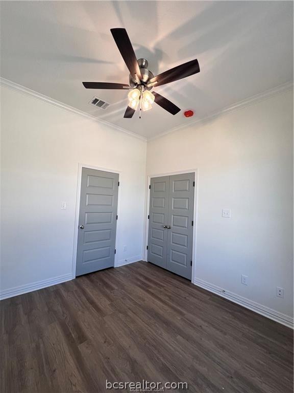 unfurnished bedroom featuring ceiling fan, dark hardwood / wood-style floors, and crown molding