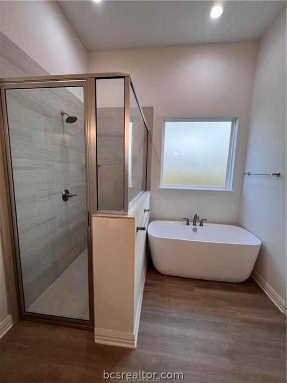 bathroom featuring wood-type flooring and shower with separate bathtub