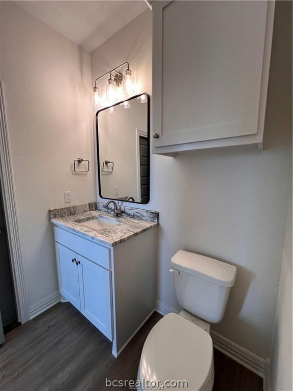 bathroom featuring toilet, vanity, and hardwood / wood-style flooring