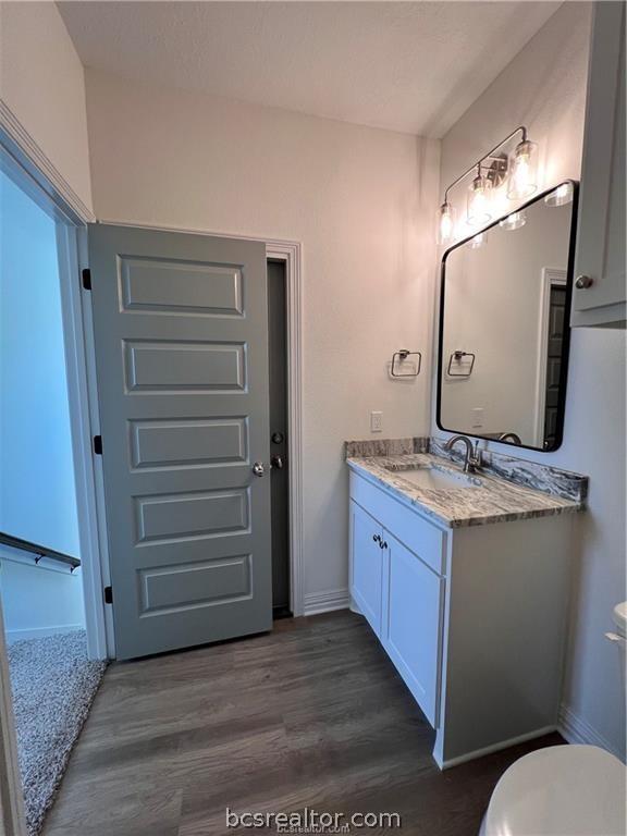 bathroom with wood-type flooring, vanity, and toilet