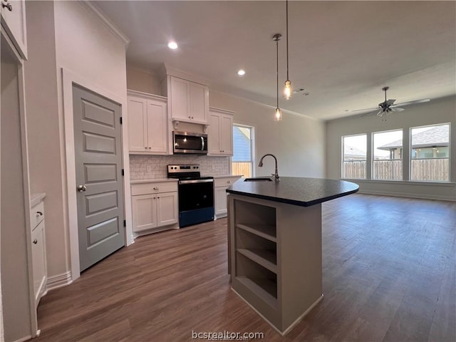 kitchen featuring stainless steel appliances, white cabinetry, a wealth of natural light, and a center island with sink