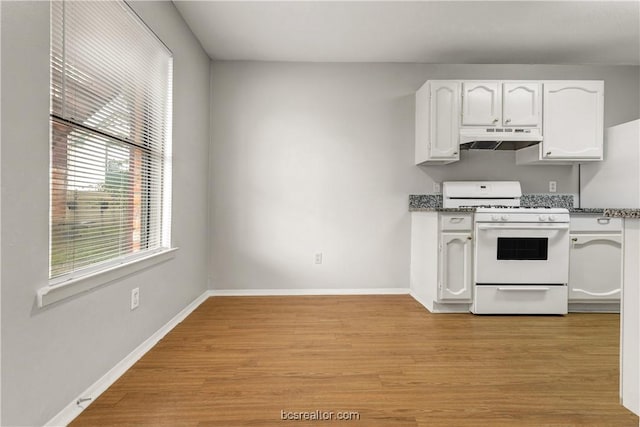 kitchen with white cabinetry, light hardwood / wood-style flooring, dark stone countertops, and white gas stove