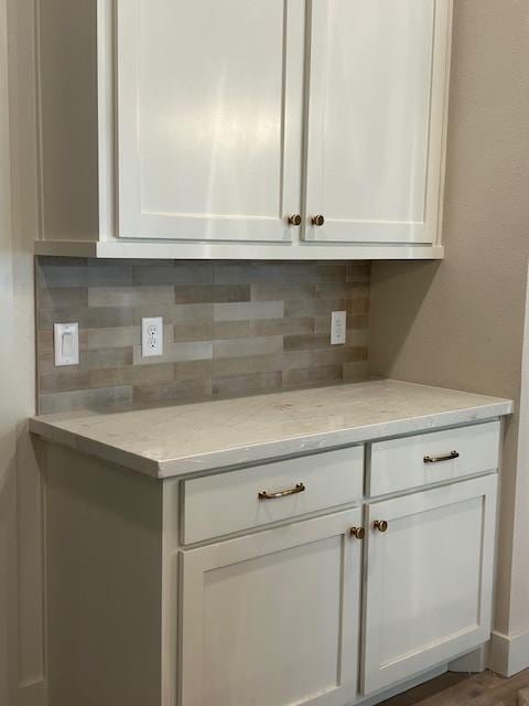 interior space with white cabinets, light stone counters, and tasteful backsplash