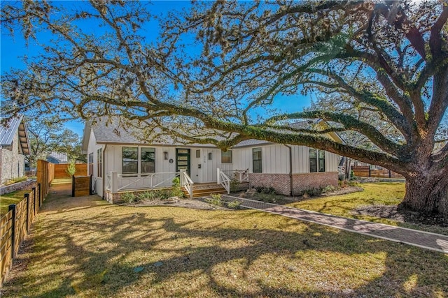 view of front of house with a front yard, fence, and brick siding