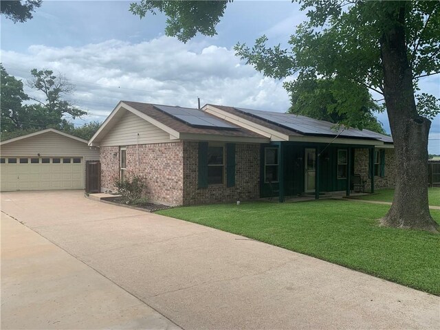 1707 Shawnee St, Navasota, TX 77868 - ranch-style house with a front lawn, a garage, solar panels, brick siding, and covered porch