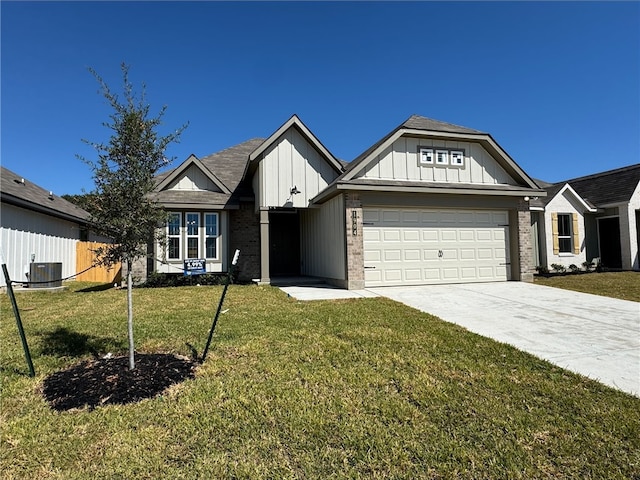 view of front of home with central air condition unit, a front lawn, and a garage