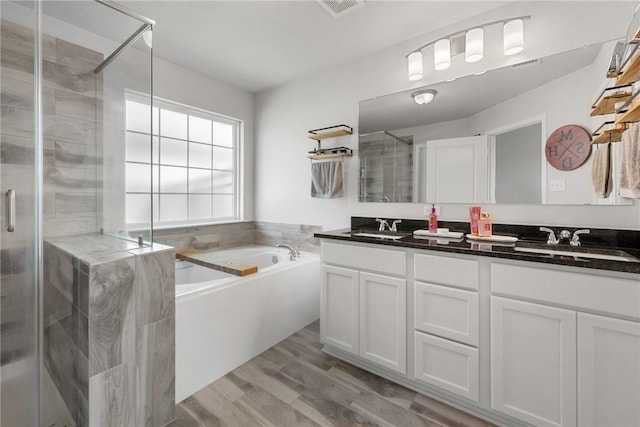 1988 Chief St, Bryan, TX 77807 - bathroom featuring double vanity, a shower stall, a garden tub, and wood finished floors