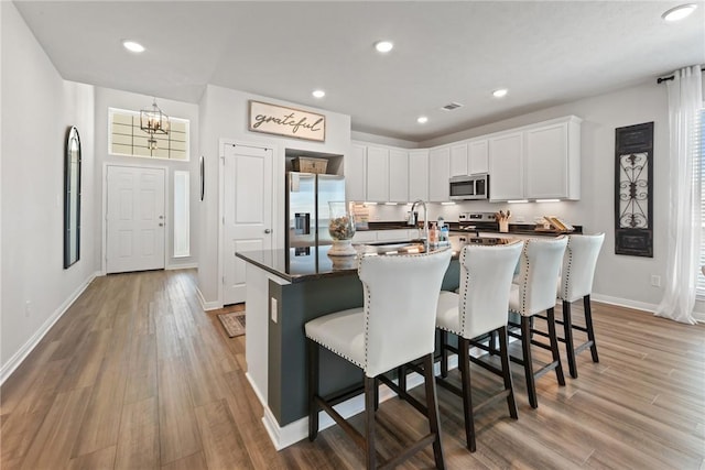 1988 Chief St, Bryan, TX 77807 - kitchen featuring stainless steel appliances, a chandelier, white cabinetry, a breakfast bar area, and dark countertops