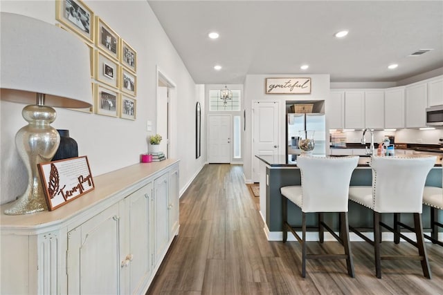1988 Chief St, Bryan, TX 77807 - kitchen featuring stainless steel appliances, a kitchen breakfast bar, dark wood-style flooring, white cabinets, and recessed lighting
