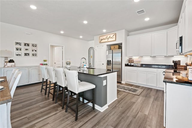 1988 Chief St, Bryan, TX 77807 - kitchen with appliances with stainless steel finishes, dark countertops, a sink, a breakfast bar, and wood finished floors