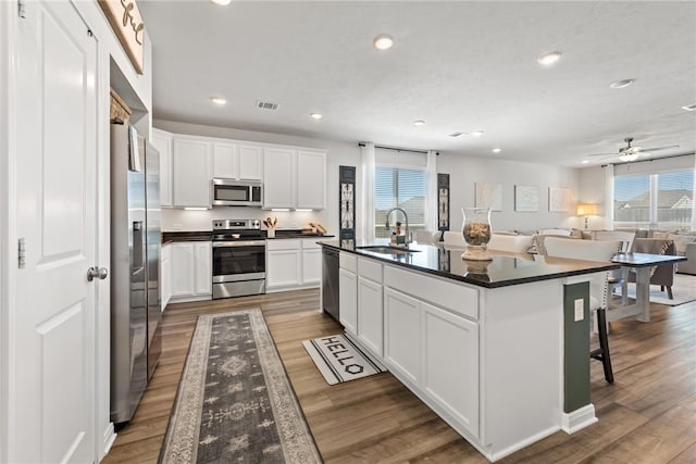 1988 Chief St, Bryan, TX 77807 - kitchen with appliances with stainless steel finishes, a sink, dark countertops, wood finished floors, and recessed lighting
