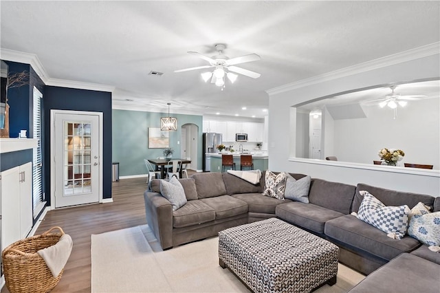 living room featuring ornamental molding, ceiling fan, and light wood-type flooring