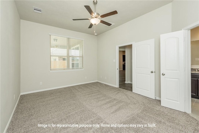 unfurnished bedroom featuring ceiling fan, ensuite bathroom, and light colored carpet