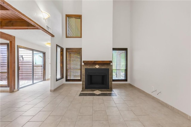 1536 Wolf Run, College Station, TX 77840 - unfurnished living room with a high ceiling, light tile patterned flooring, a tile fireplace, and baseboards