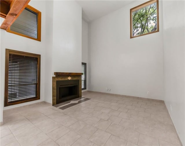 1536 Wolf Run, College Station, TX 77840 - unfurnished living room with a high ceiling, tile patterned flooring, a fireplace with flush hearth, and baseboards