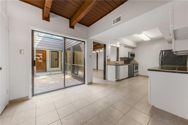 1536 Wolf Run, College Station, TX 77840 - kitchen with range, freestanding refrigerator, dark countertops, stainless steel microwave, and white cabinets