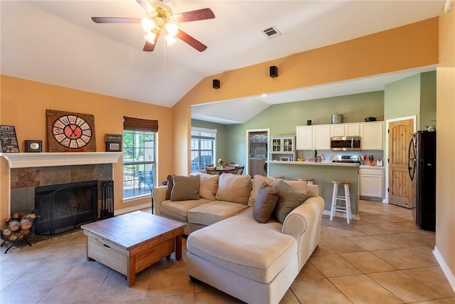 1701 Bradley Rd, College Station, TX 77845 - living room featuring vaulted ceiling, light tile patterned floors, a ceiling fan, a fireplace, and baseboards