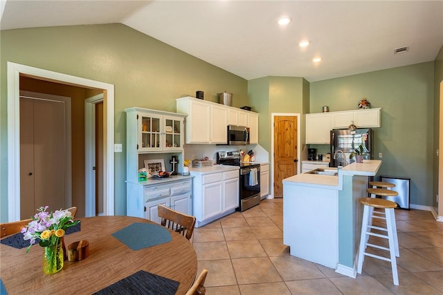 1701 Bradley Rd, College Station, TX 77845 - kitchen featuring stainless steel appliances, a sink, light tile patterned flooring, white cabinetry, and vaulted ceiling