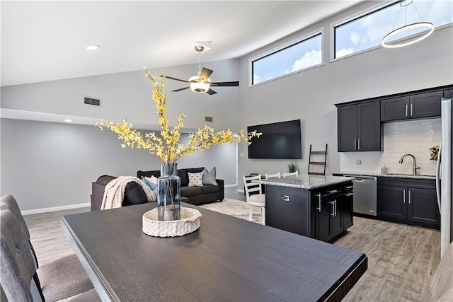 dining area with light wood-type flooring, high vaulted ceiling, baseboards, and visible vents