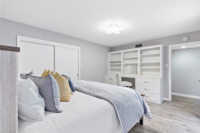 bedroom featuring a closet, visible vents, baseboards, and wood finished floors