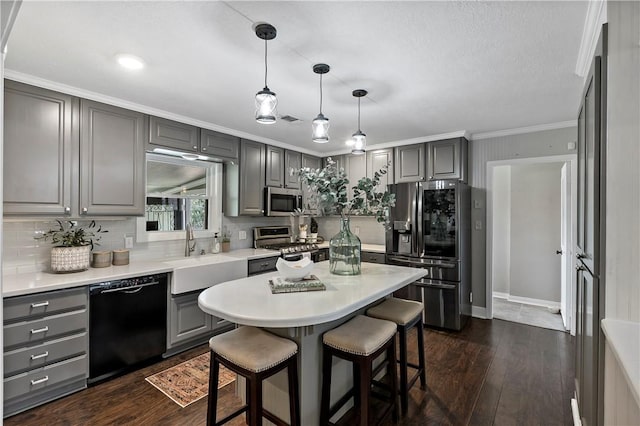 kitchen with dark wood finished floors, a sink, gray cabinetry, appliances with stainless steel finishes, and a kitchen breakfast bar