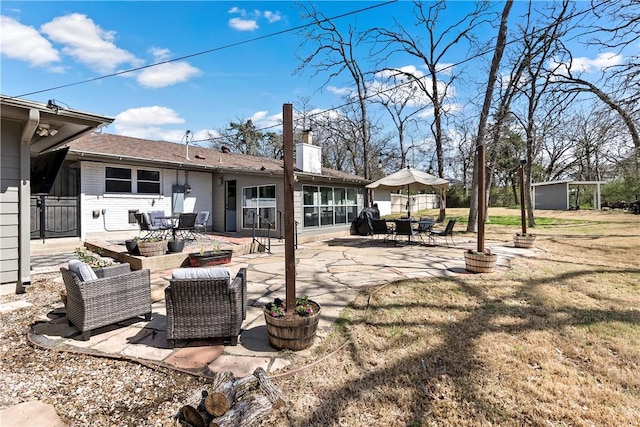 back of house with brick siding, a chimney, outdoor dining area, a yard, and a patio area