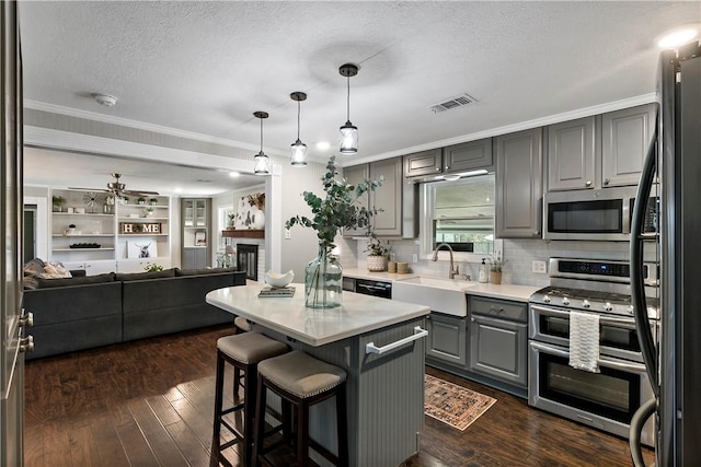 kitchen with visible vents, gray cabinets, appliances with stainless steel finishes, a fireplace, and a sink