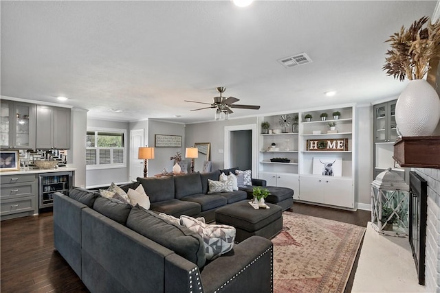 living area featuring visible vents, beverage cooler, dark wood finished floors, a fireplace, and ceiling fan