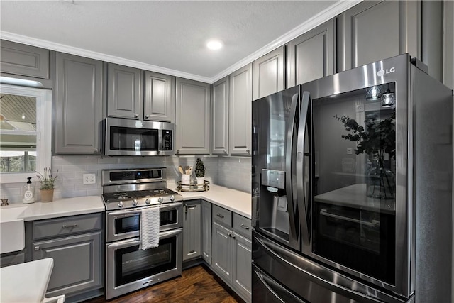 kitchen featuring stainless steel appliances, decorative backsplash, gray cabinets, and light countertops