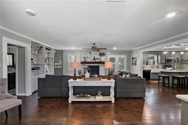 living area featuring crown molding, dark wood-type flooring, recessed lighting, a fireplace, and a ceiling fan