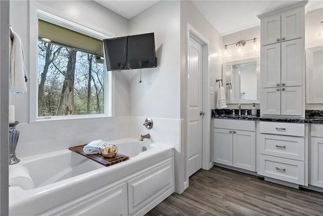 full bath with vanity, a bath, and wood finished floors