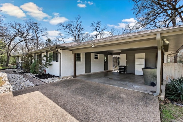 exterior space featuring brick siding, an attached carport, and driveway