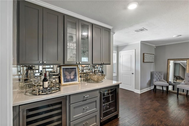 bar with beverage cooler, visible vents, a bar, and crown molding