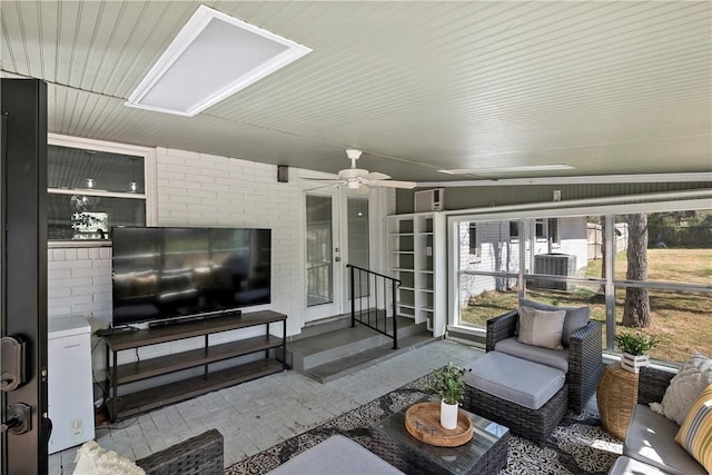 living area featuring brick wall and a ceiling fan