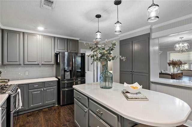 kitchen with gray cabinetry, dark wood finished floors, light countertops, ornamental molding, and appliances with stainless steel finishes