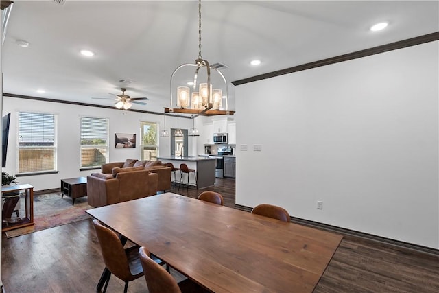 dining room with crown molding, dark hardwood / wood-style flooring, ceiling fan with notable chandelier, and sink