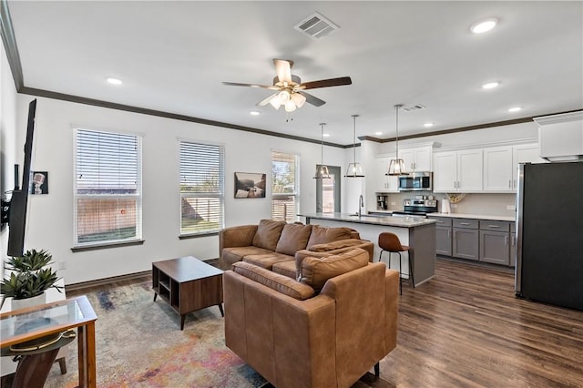 living room featuring hardwood / wood-style flooring, ceiling fan, sink, and crown molding