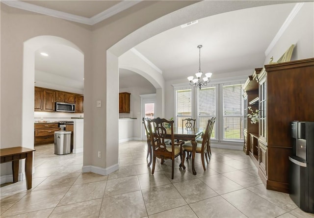 8305 Raintree Dr, College Station, TX 77845 - dining space featuring ornamental molding, baseboards, a chandelier, arched walkways, and light tile patterned floors