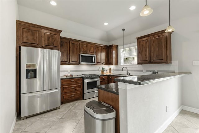 8305 Raintree Dr, College Station, TX 77845 - kitchen featuring appliances with stainless steel finishes, a sink, dark countertops, hanging light fixtures, and a peninsula