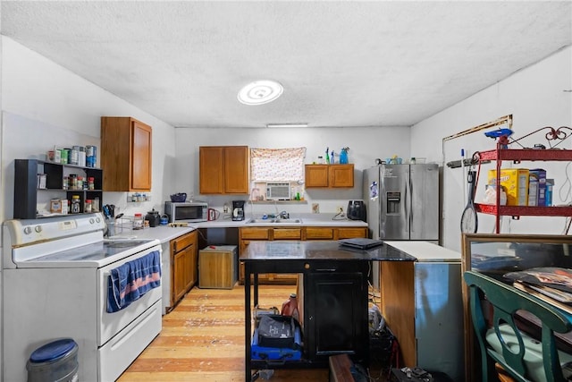 kitchen with light wood-style flooring, appliances with stainless steel finishes, a sink, light countertops, and brown cabinets