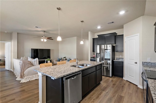 kitchen featuring a center island with sink, sink, ceiling fan, wood-type flooring, and stainless steel appliances