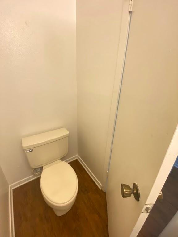 bathroom with wood finished floors, toilet, and baseboards