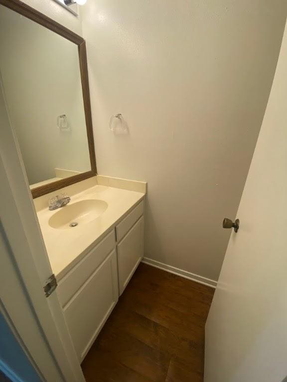 bathroom featuring baseboards, wood finished floors, and vanity