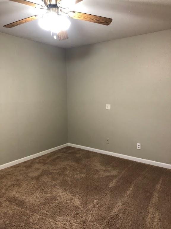 carpeted spare room featuring a ceiling fan and baseboards