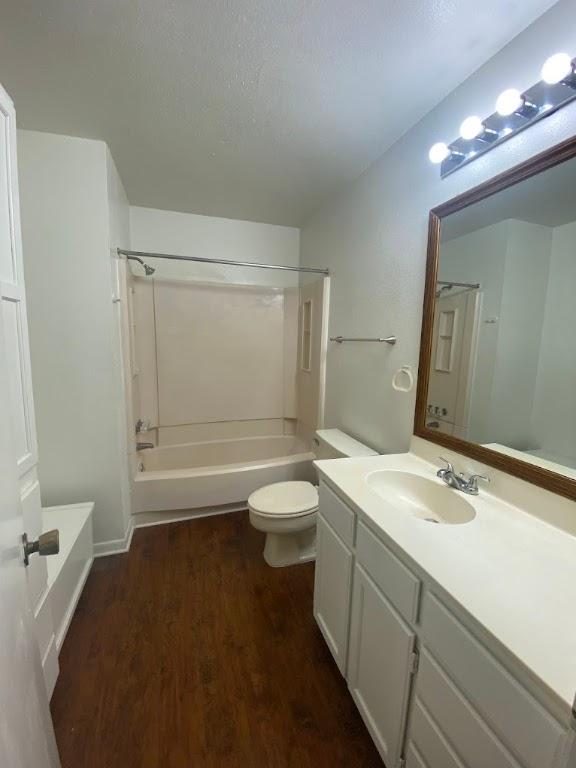 bathroom featuring toilet, washtub / shower combination, a textured ceiling, vanity, and wood finished floors